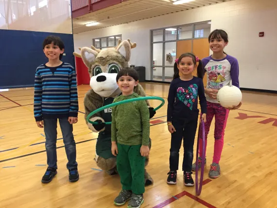 a group of children with hula hoops posing with the Wisconsin Herd mascot.