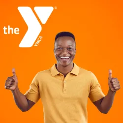A man wearing a polo smiling and giving two thumbs up under the YMCA logo. 