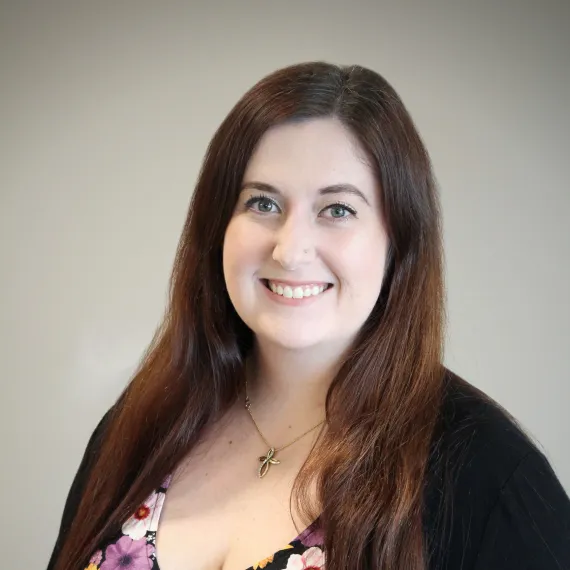 A photo of Taylor douglas. Taylor has blue eyes and long brown hair and is wearing a floral blouse. 