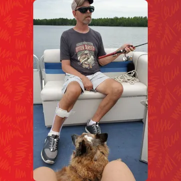 Greg on a boat with a dog, fishing.