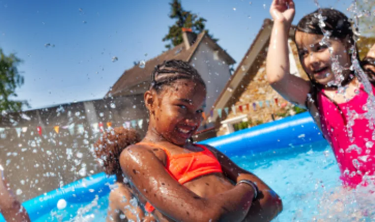 A group of young children splashing around in a backyard pool.
