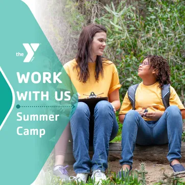 A camp counselor sitting outside with a group of campers.