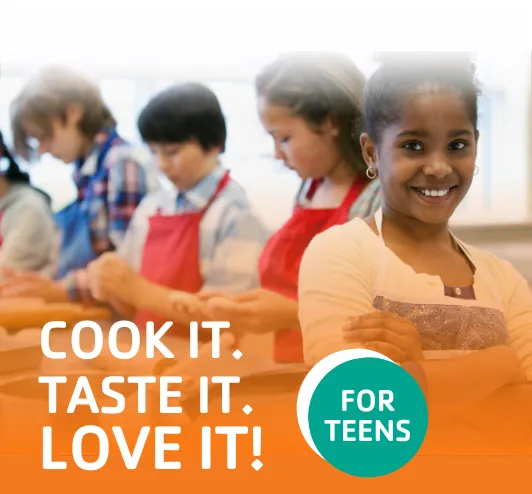 A group of teens with aprons on in a cooking class.