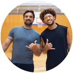 Two men on the basketball court giving a thumbs up.