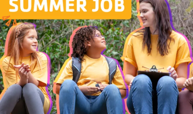 A camp counselor sitting outside with a group of campers. 