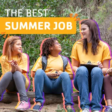 A camp counselor sitting outside with a group of campers. 