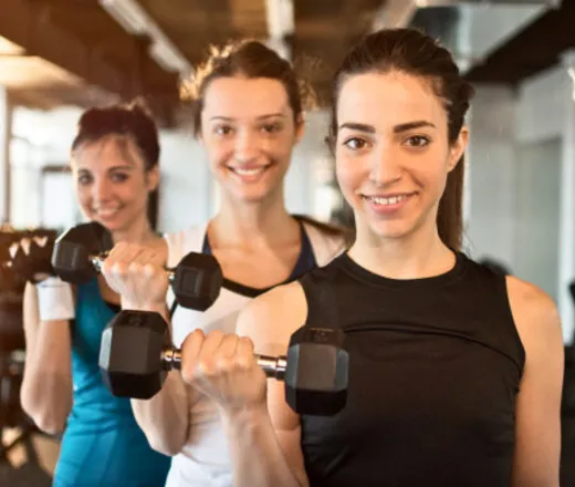 3 teenage girls in gym attire each lifting a 10 pound dumb bell.