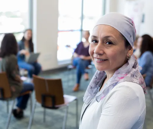 a woman wearing a head scarf who is attending a support group with other cancer survivors.