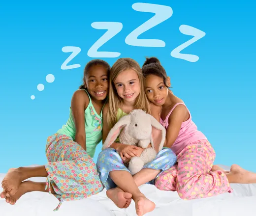 A group of kids in their pajamas and holding a stuffed animal.