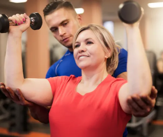 Woman lifting weights with trainer.