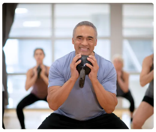 an older gentleman squatting with a dumbbell.
