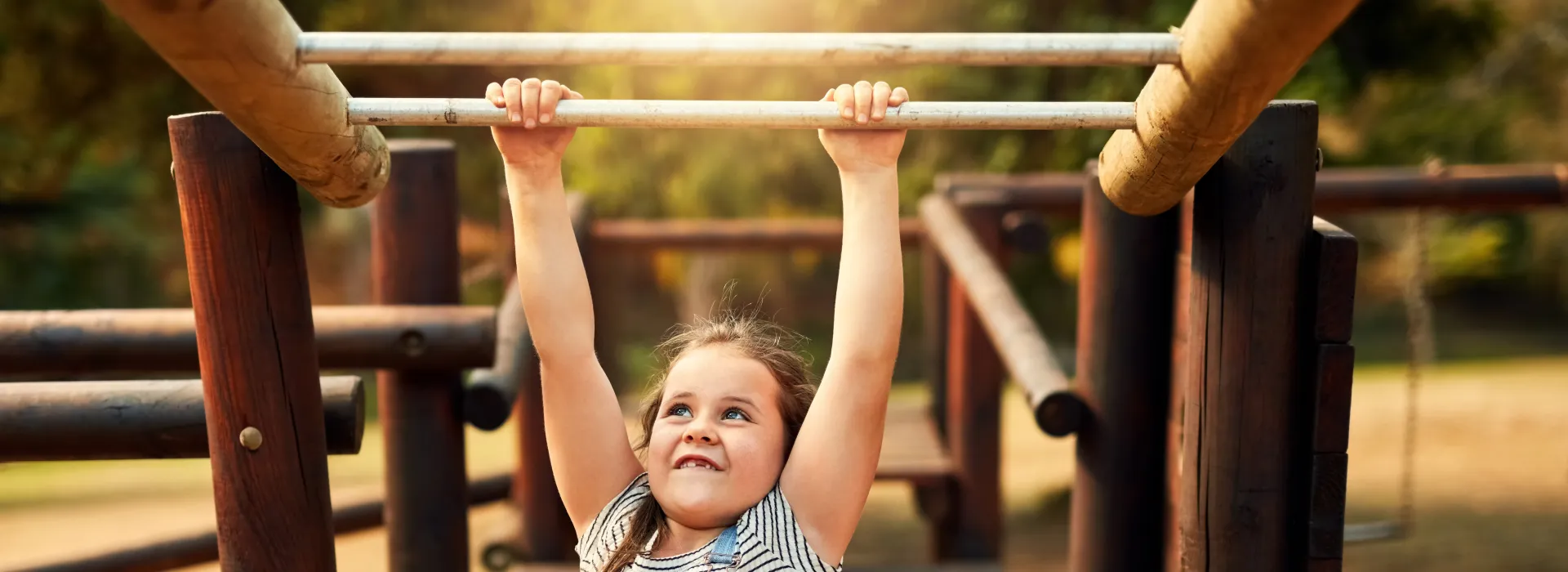 A little girl swinging on the monkey bars.