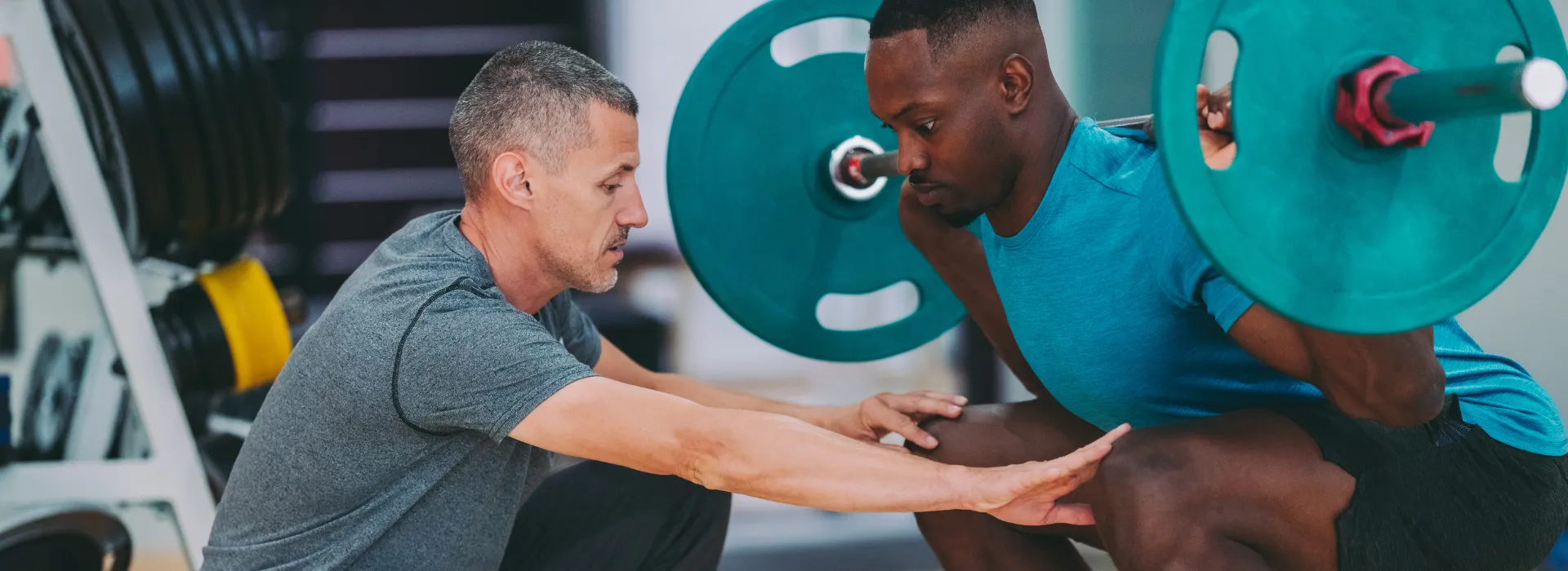 Personal trainer assisting with a lift