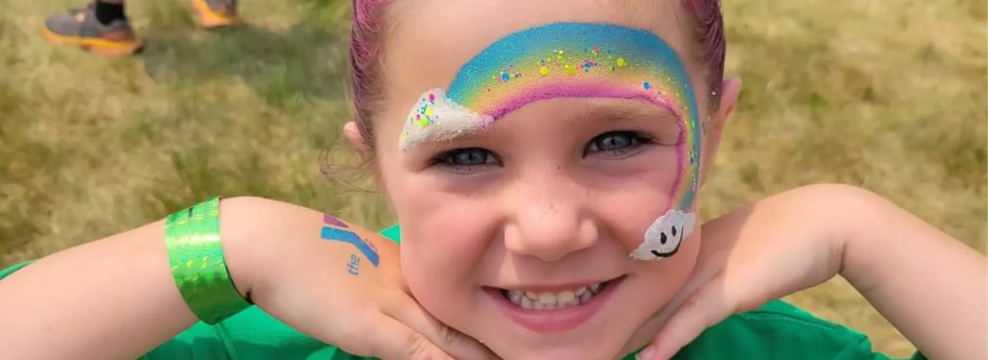 A young girl with rainbow face paint at family fun fest