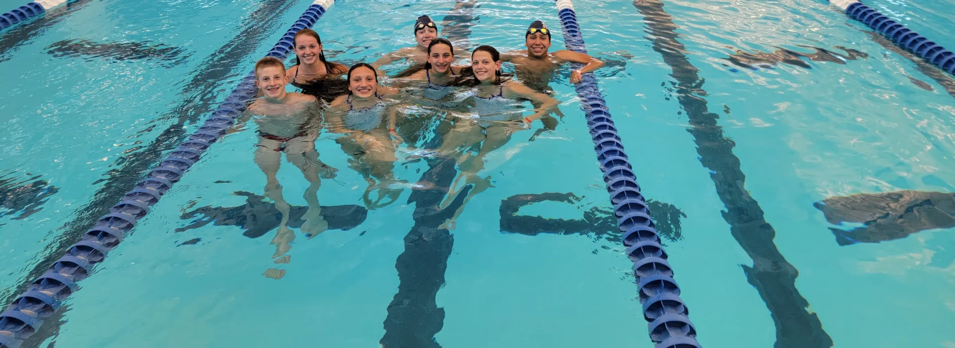 7 teen age swimmers smiling in the 20th ave pool during OSHY swim practice.