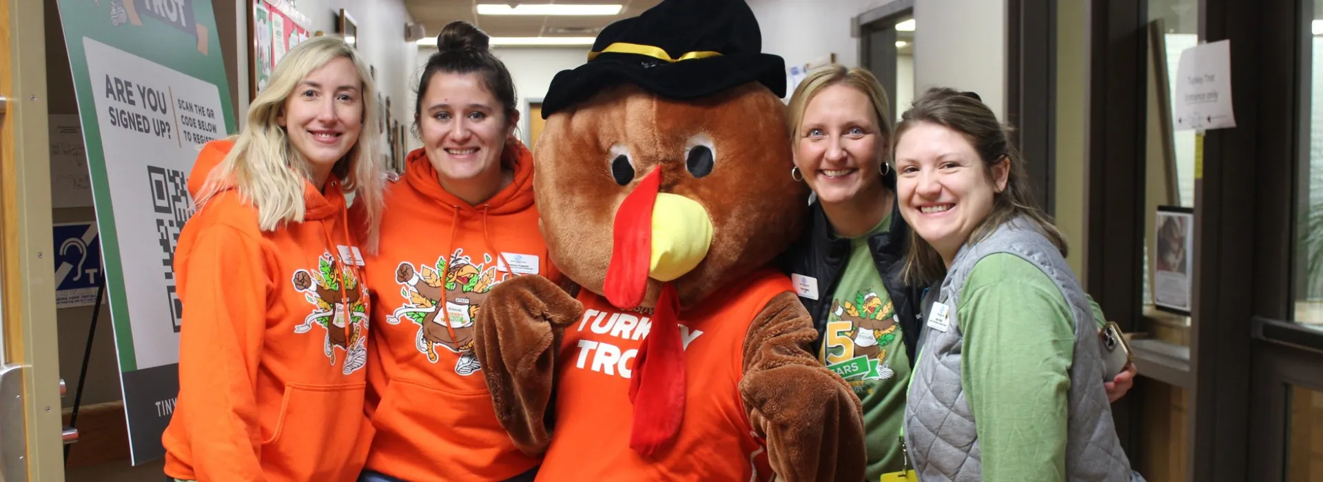 a group of turkey trot volunteers with the turkey mascot.