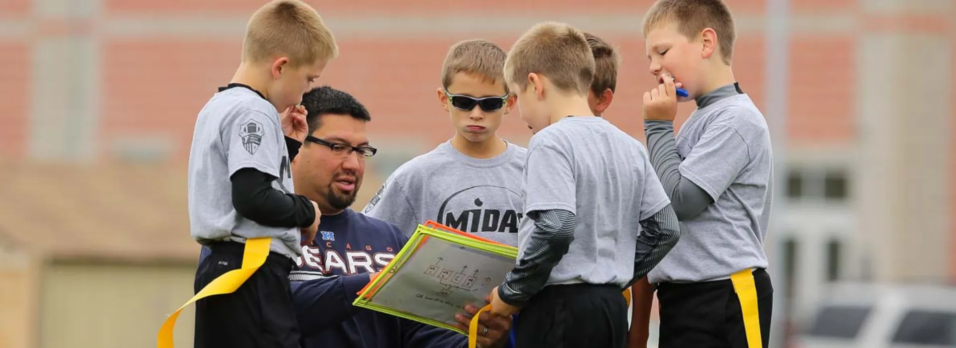 A volunteer coach reviewing plays with the boys flag football team.