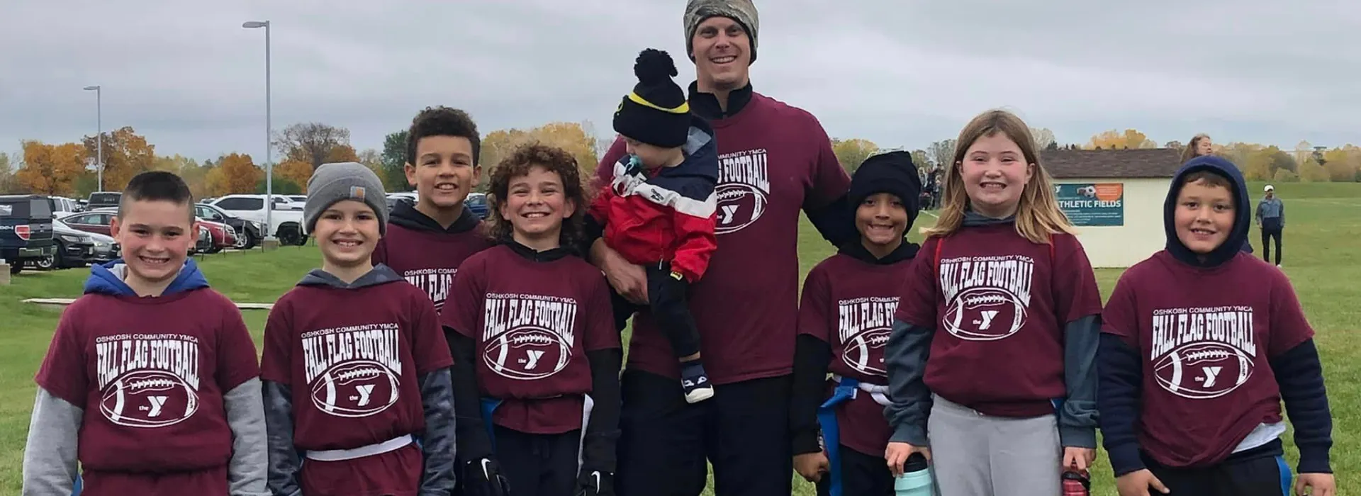 A volunteer coach smiling with the youth flag football team.