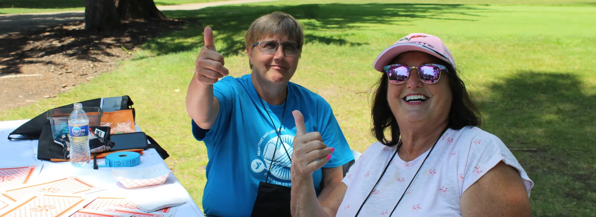Two women giving the thumbs up while running a game at the Y golf outing.